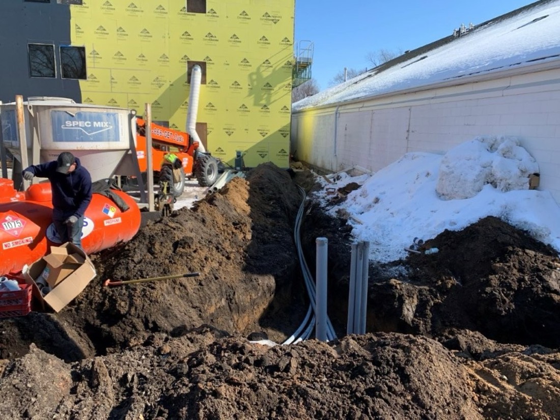 The same location after thawing, with the ground excavated, conduit risers set, and underground feeders run.